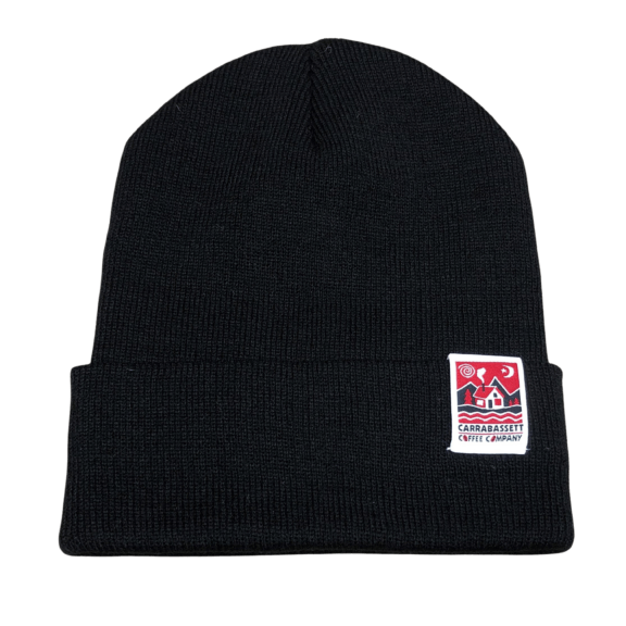 Photograph of a black, knit winter hat with a rolled brim. The Carrabassett Coffee Company square house logo (in red) is on a white tag on the left side.