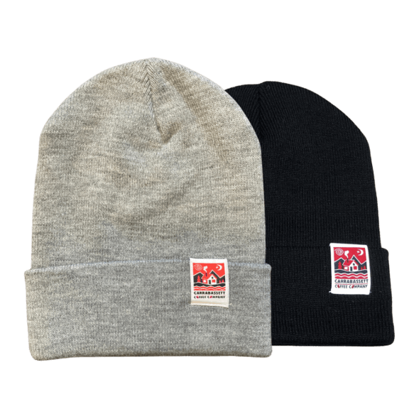 two knit hats with the Carrabassett Coffee company logo on the right hand side of the folded brim. One is light gray, the other is black.