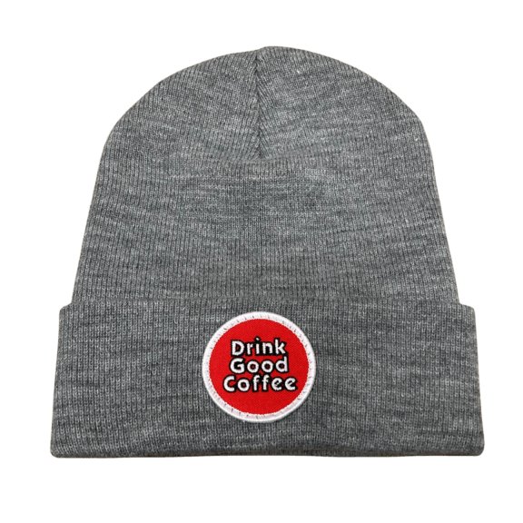 Photograph of a gray, knit winter hat with a rolled brim. The Carrabassett Coffee Company Drink Good Coffee round logo patch in the center.