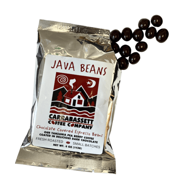 Photograph of a silver colored packet containing chocolate covered epsresso beans. The words: Java Beans are written in red across the top, above the Carrabassett Coffee company logo. Text below the logo reads: "Chocolate Covered Espresso Beans. Our Tanzania Peaberry Coffee coated in delicious dark chocolate. Fresh Roasted- Small Batches. Net weight 4 oz (113g)." The packet is open on the top right corner and chocolate covered espresso beans are spilling out.