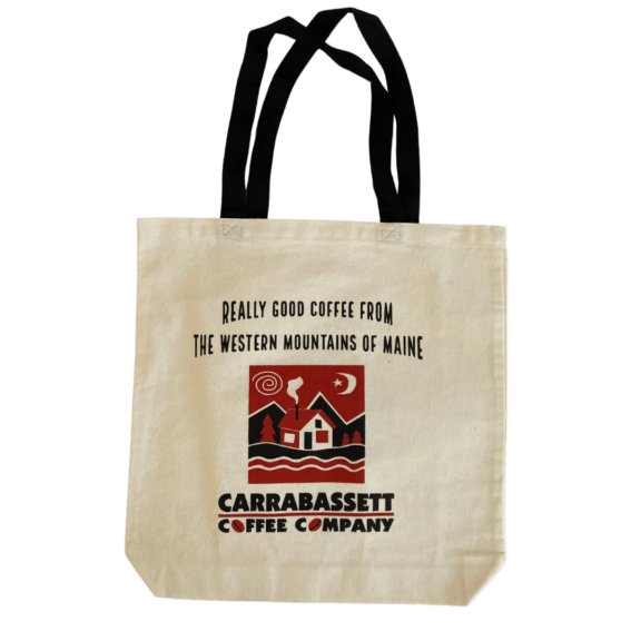 Photograph of the logo Canvas tote bag. Shown here is the front of the bag. The words "Really Good Coffee from the Western Mountains of Maine" in black at the top, above the Carrabassett Coffee Company logo. The bag is natural canvas color with black straps.
