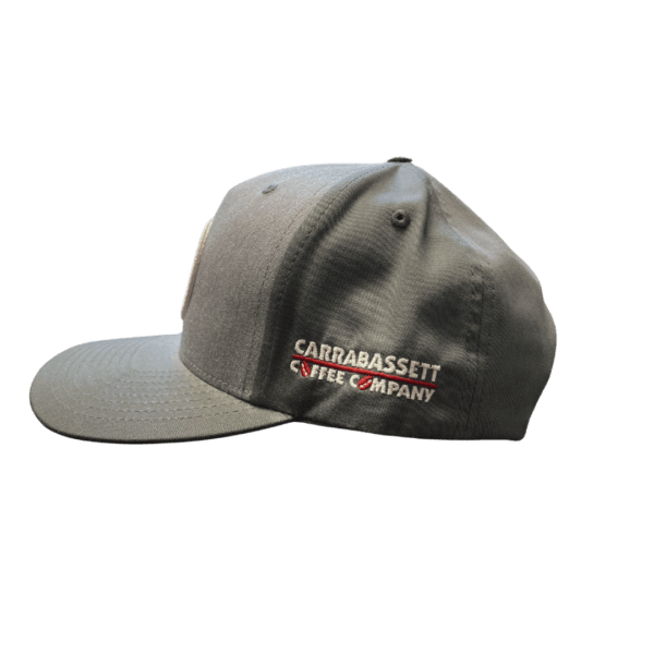 Photo of a 2-tone gray baseball cap with red circle on the front. Inside the circle are the words: Drink Good Coffee. On the side of the hat are the words: Carrabassett Coffee Company.